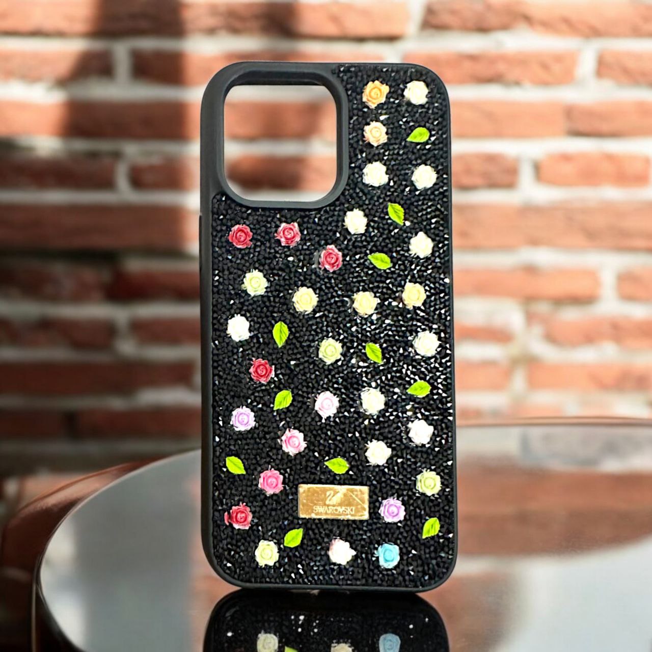 Elegant black iPhone case with floral embellishments, iphone 15 cover featuring a sparkling crystal design with delicate rose accents for
