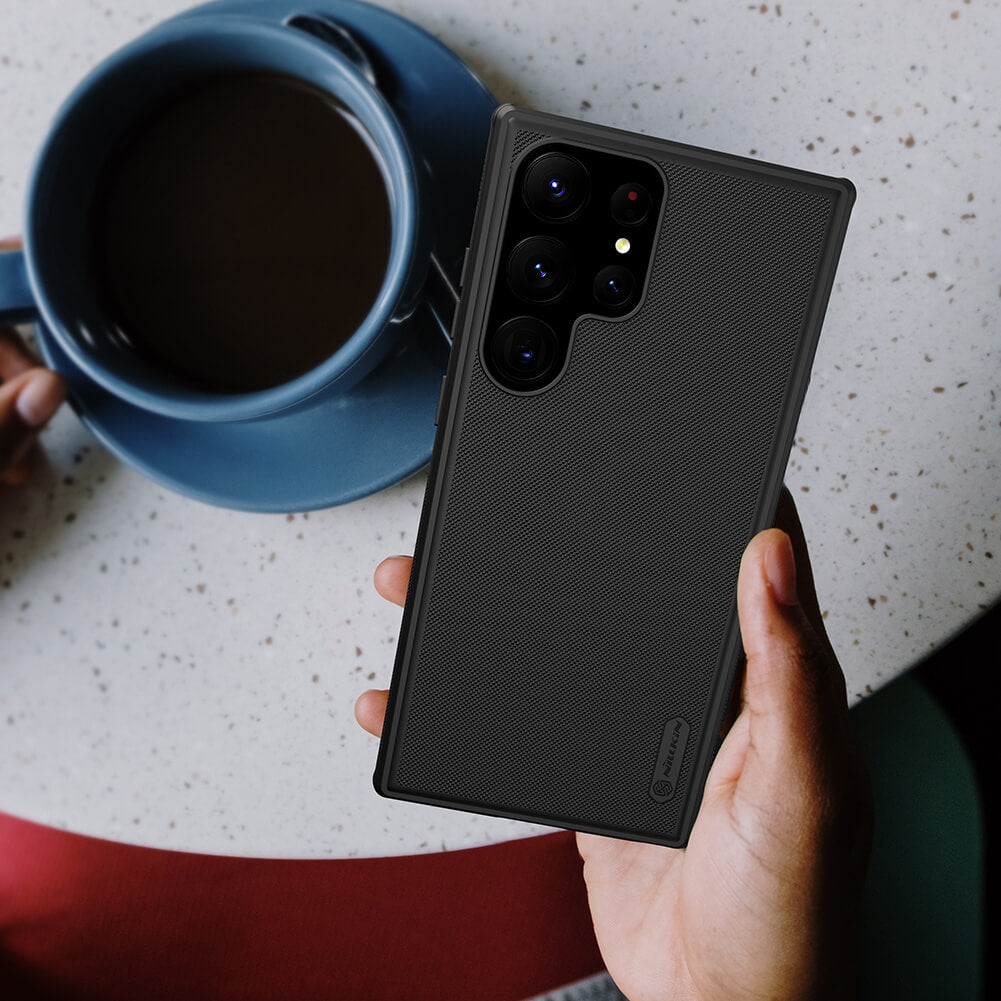 Black matte Samsung cover held in hand next to a coffee cup, s23 ultra cover showing minimalistic back design and fine finish