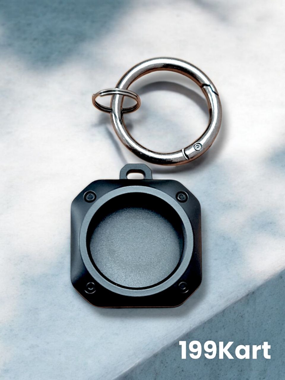 Single empty black metal AirTag cover with rounded edges and a loop ring