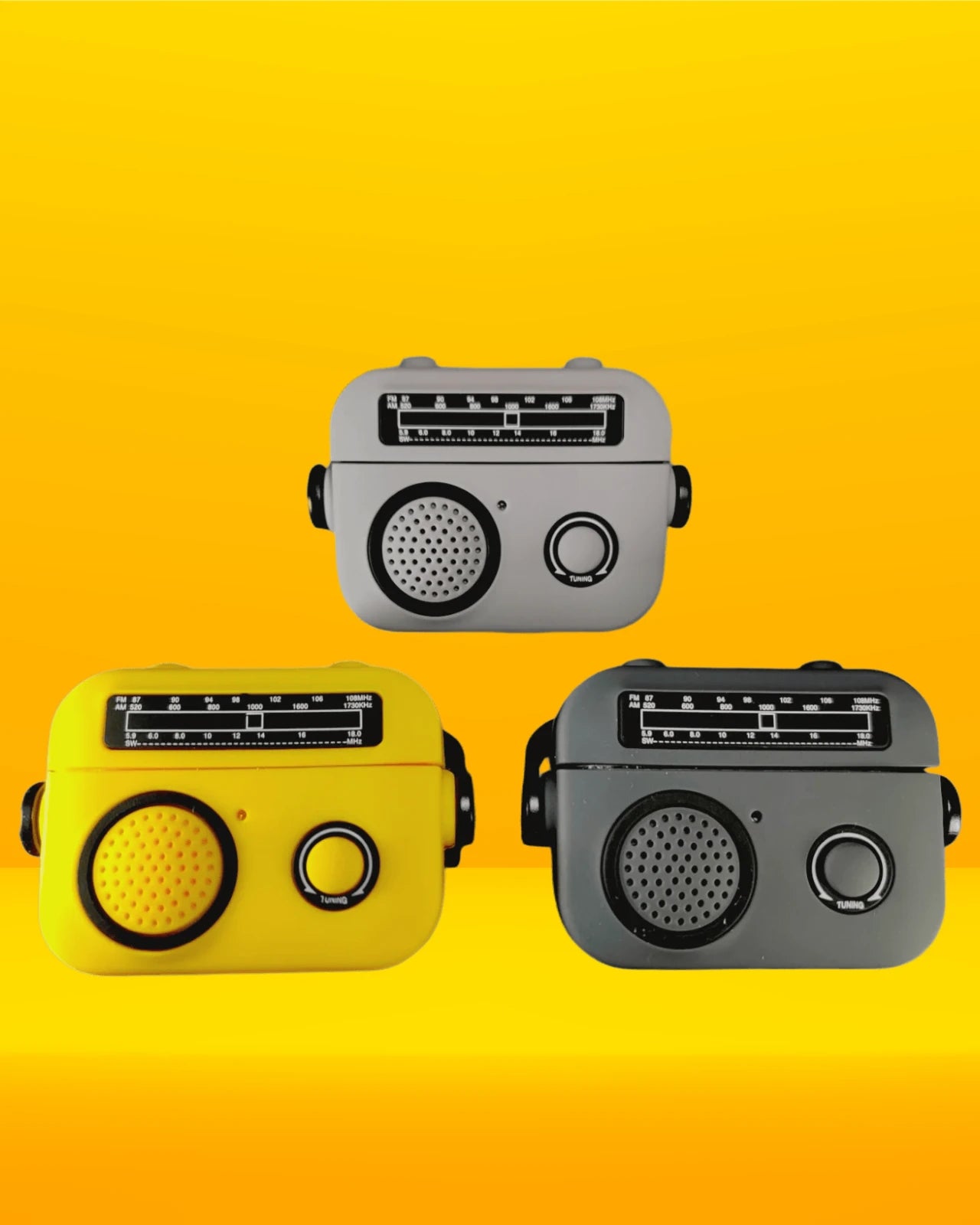 A set of three radio style airpods pro 2 case in yellow, dark grey, and light grey placed between potted plants on a white surface.