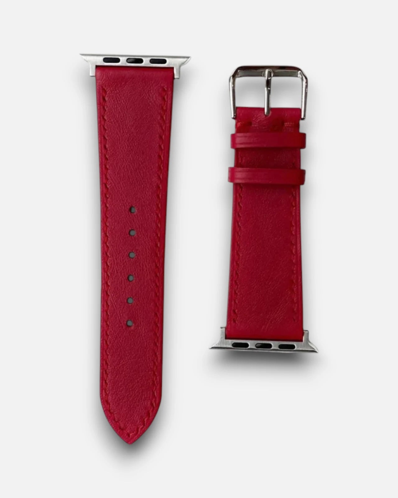 A detailed view of a red leather apple watch straps, complete with a shiny silver buckle for a chic look.