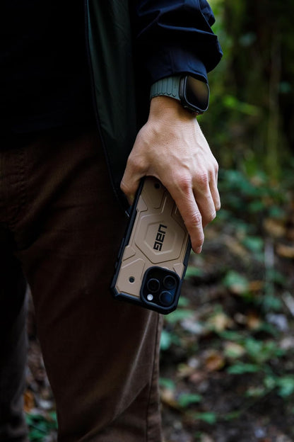 A man in the woods holds a rugged iPhone cover, iphone 16 pro max cover showcasing its durable design for outdoor adventures